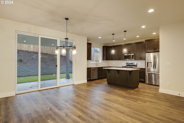 kitchen featuring hardwood / wood-style floors, stainless steel appliances, and hanging light fixtures