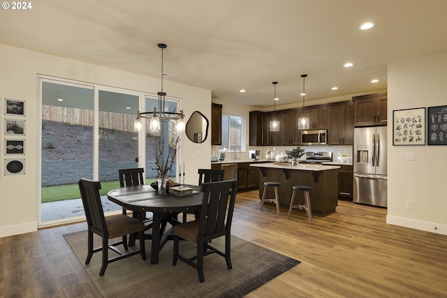 dining area with sink, a chandelier, and light wood-type flooring