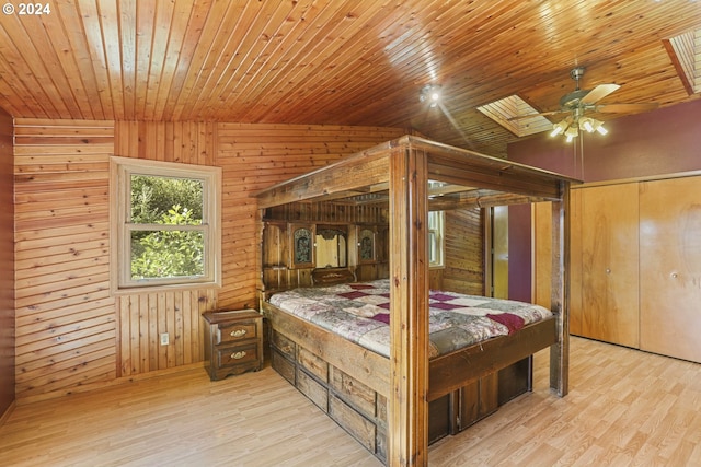 bedroom with light hardwood / wood-style floors, wood walls, wooden ceiling, and vaulted ceiling with skylight