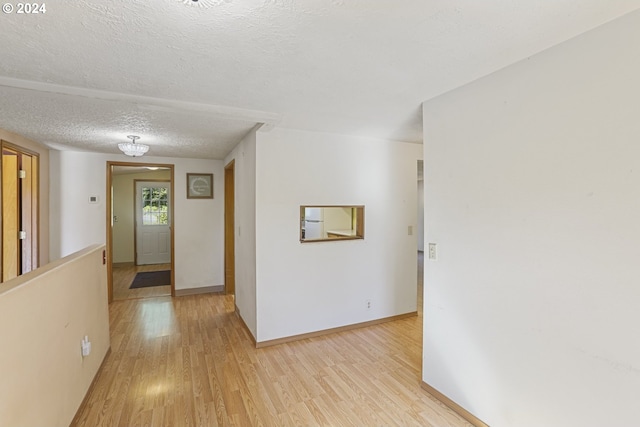 hallway featuring light hardwood / wood-style flooring and a textured ceiling