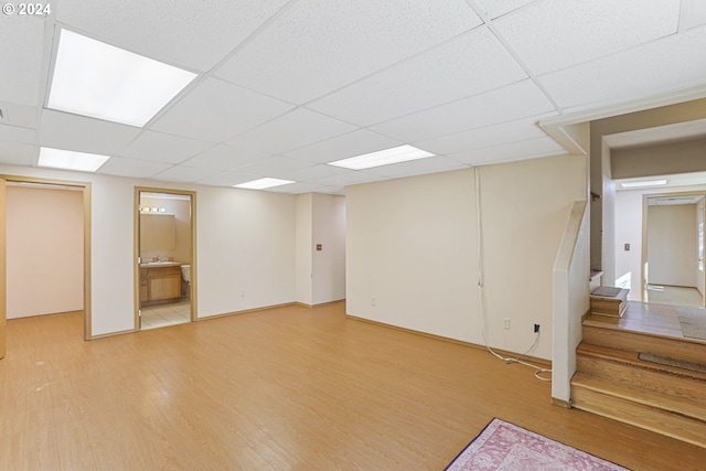 basement with light hardwood / wood-style floors and a paneled ceiling