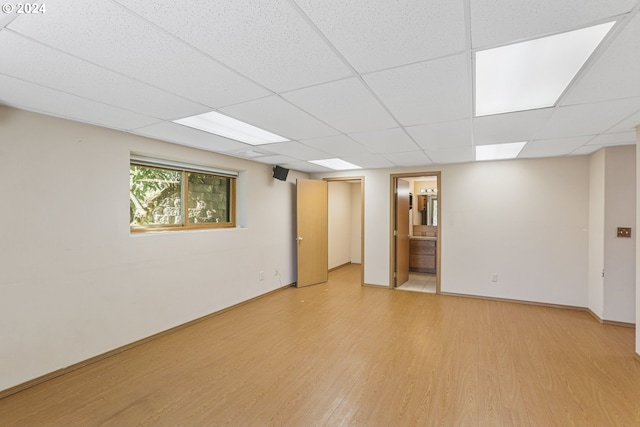 basement with a paneled ceiling and light wood-type flooring