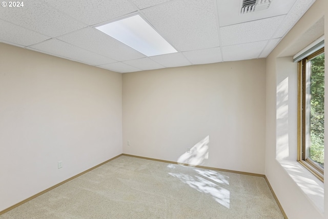 carpeted spare room featuring a drop ceiling