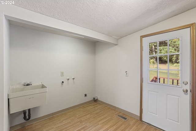 laundry room with hookup for a washing machine, hookup for an electric dryer, light wood-type flooring, sink, and a textured ceiling