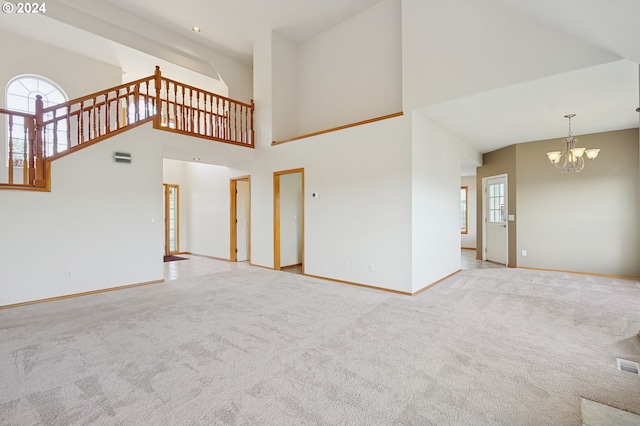 unfurnished living room with a towering ceiling, light carpet, and a chandelier