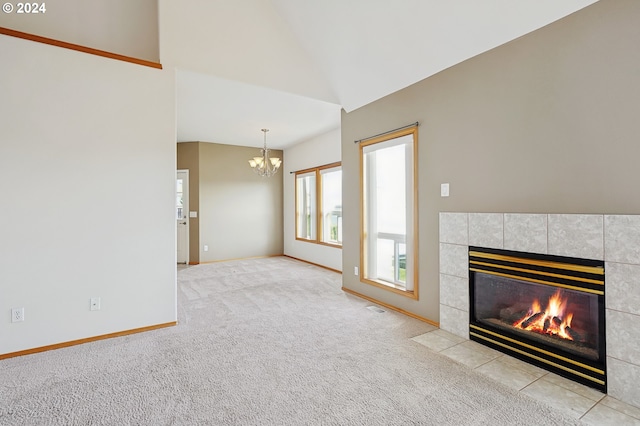 unfurnished living room with a notable chandelier, a fireplace, lofted ceiling, and light carpet