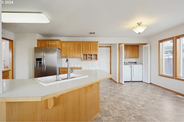 kitchen featuring stainless steel fridge, independent washer and dryer, a kitchen breakfast bar, and sink