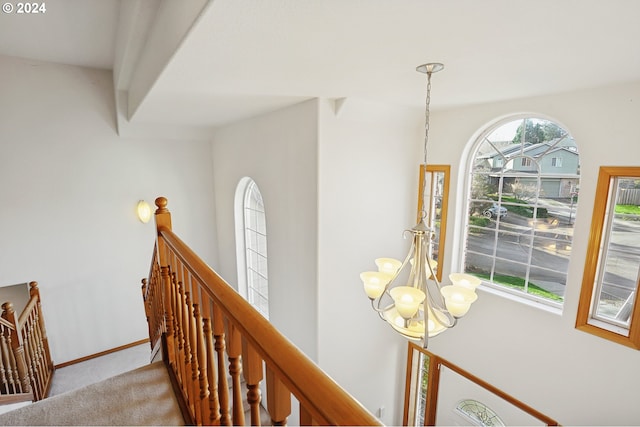 corridor featuring light carpet and a chandelier