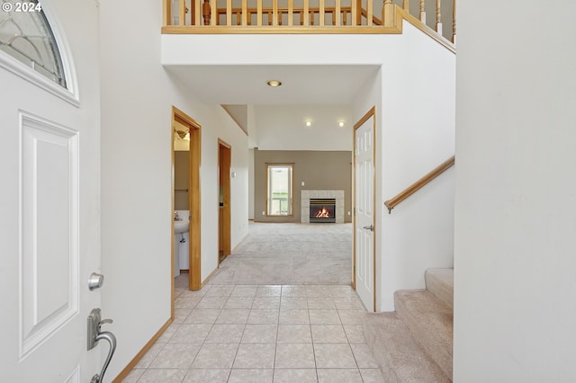 carpeted entrance foyer with a fireplace and a high ceiling