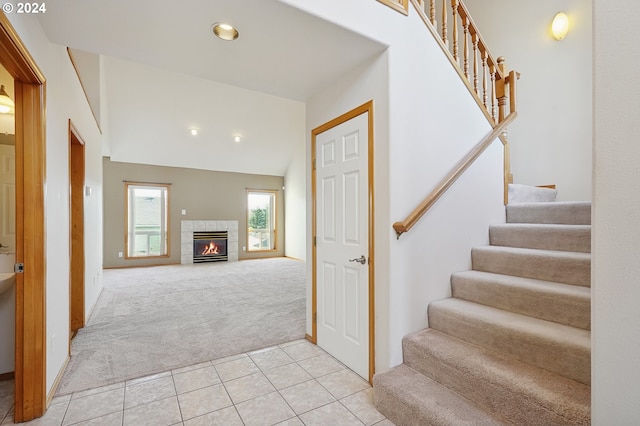 stairway featuring carpet, a tile fireplace, and vaulted ceiling