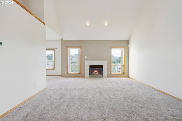 unfurnished living room featuring light carpet, a fireplace, and high vaulted ceiling