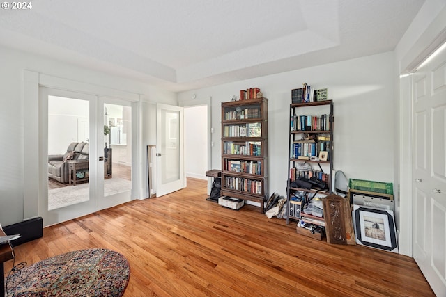 sitting room with a tray ceiling, hardwood / wood-style flooring, and french doors