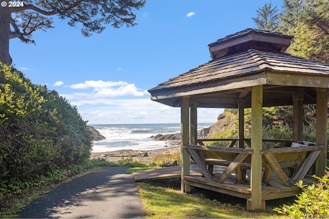 view of property's community with a gazebo, a water view, and a beach view