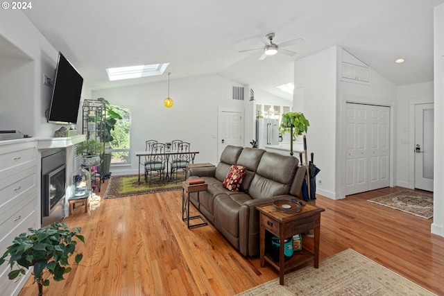 living room featuring light hardwood / wood-style flooring, ceiling fan, and lofted ceiling with skylight