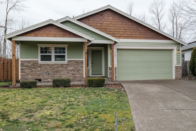 craftsman-style house with fence, a garage, stone siding, driveway, and a front lawn