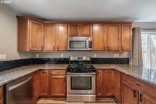 kitchen featuring stone counters, stainless steel appliances, and light hardwood / wood-style floors