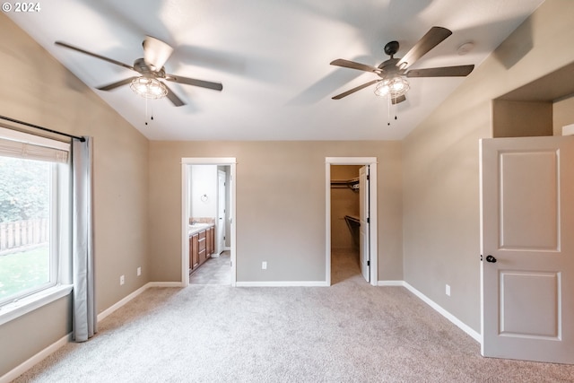 unfurnished bedroom with ceiling fan, a spacious closet, and multiple windows