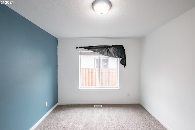 carpeted empty room featuring a textured ceiling