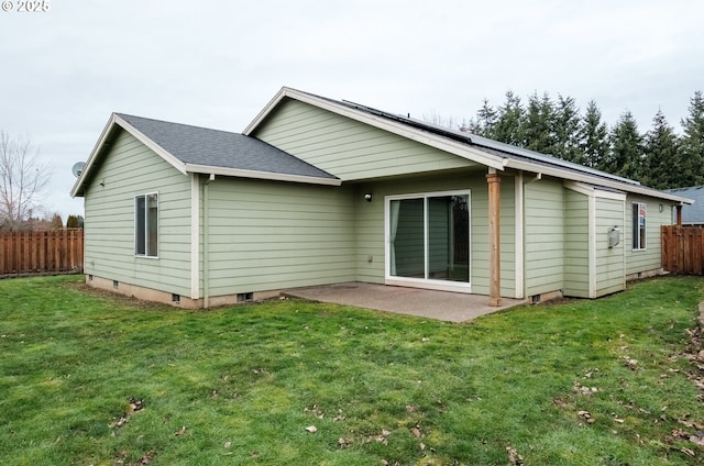 back of house featuring a shingled roof, a patio, fence, and a lawn