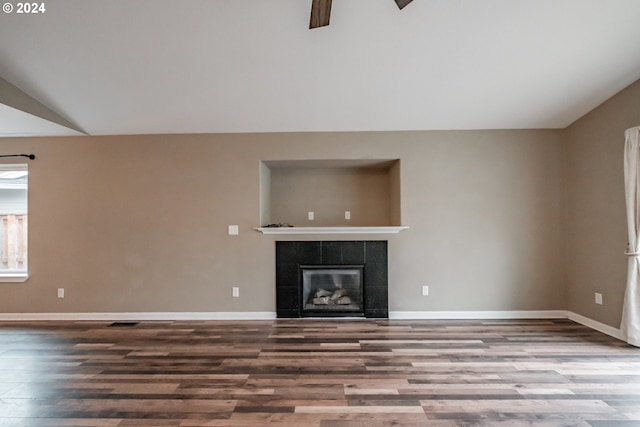 unfurnished living room with hardwood / wood-style floors, built in shelves, lofted ceiling, and a tiled fireplace