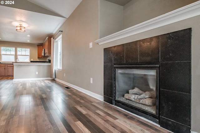 unfurnished living room with a fireplace, wood-type flooring, and vaulted ceiling