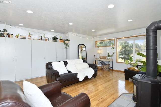 living room with light hardwood / wood-style flooring, a textured ceiling, and a wood stove