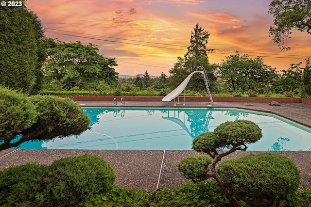 pool at dusk featuring a water slide