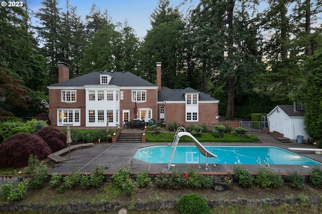 exterior space featuring an outdoor structure, a water slide, a diving board, and a patio area