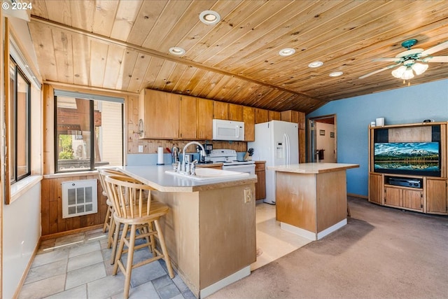 kitchen with lofted ceiling, white appliances, sink, a kitchen island, and kitchen peninsula