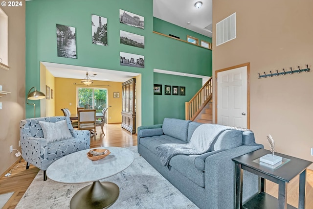 living room featuring visible vents, a towering ceiling, wood finished floors, baseboards, and stairway