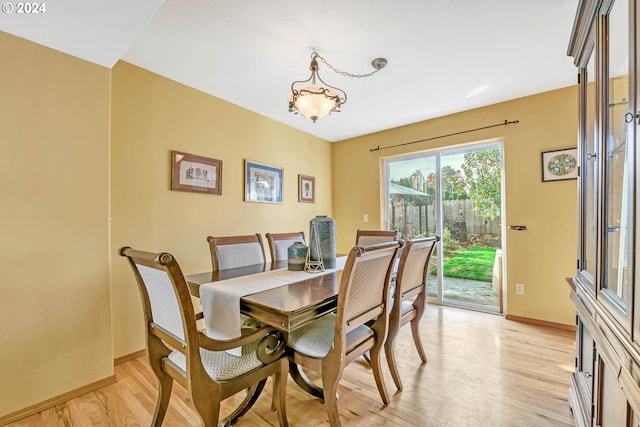 dining room with baseboards, a notable chandelier, and light wood finished floors