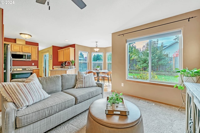 living room featuring sink, light carpet, and ceiling fan