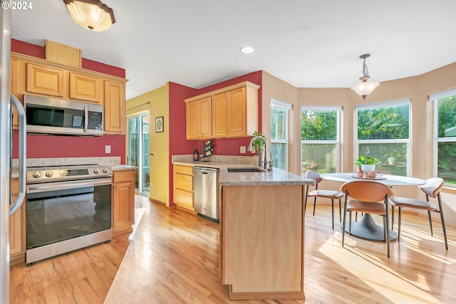 kitchen featuring hanging light fixtures, stainless steel appliances, sink, light wood-type flooring, and light brown cabinetry