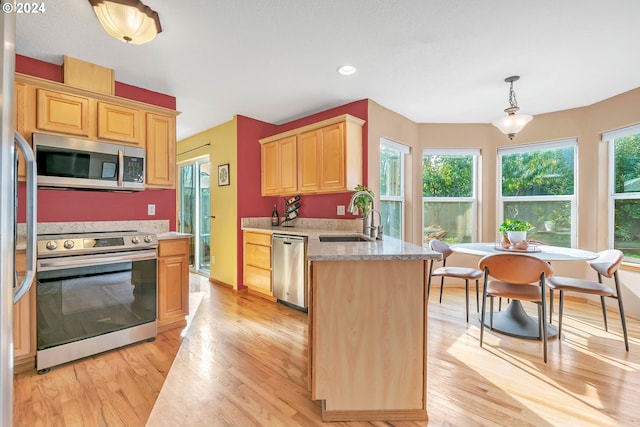 kitchen with a sink, appliances with stainless steel finishes, light brown cabinets, and light wood-style flooring