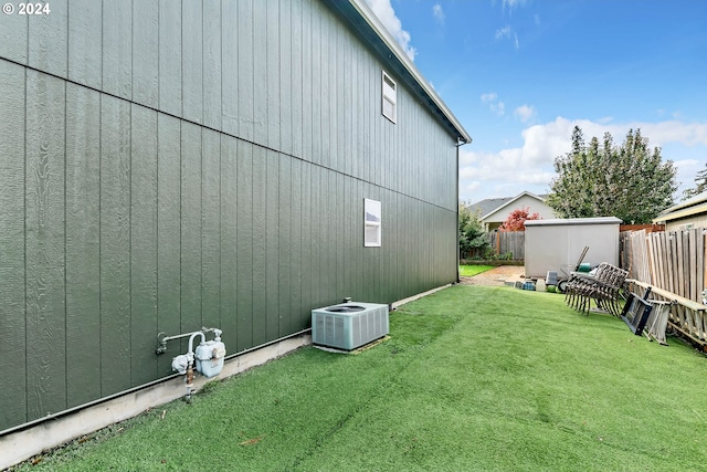 view of side of home featuring a storage unit, a yard, and central AC unit