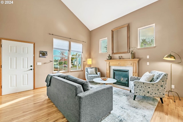 living room with light hardwood / wood-style floors, high vaulted ceiling, and a tile fireplace