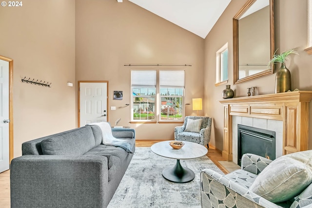 living room with a tile fireplace, high vaulted ceiling, and light hardwood / wood-style floors