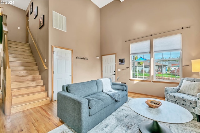 living room with light hardwood / wood-style floors and high vaulted ceiling