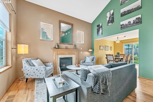 living room with light hardwood / wood-style flooring, a fireplace, and high vaulted ceiling