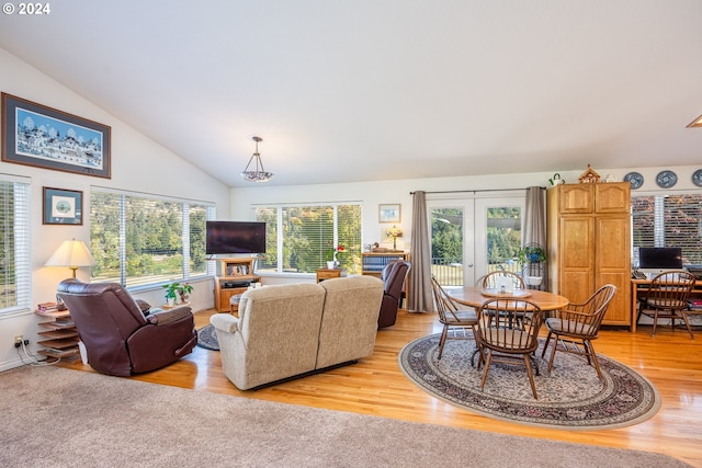 living room with french doors, lofted ceiling, plenty of natural light, and light hardwood / wood-style floors