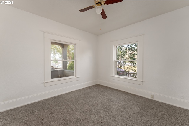 spare room with dark colored carpet, ceiling fan, and a wealth of natural light