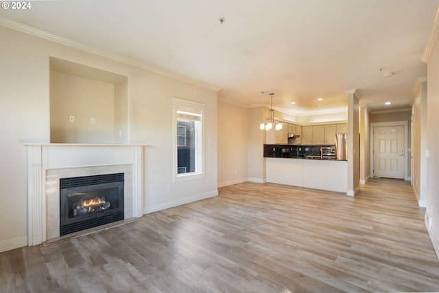 unfurnished living room with light wood-type flooring, an inviting chandelier, and ornamental molding