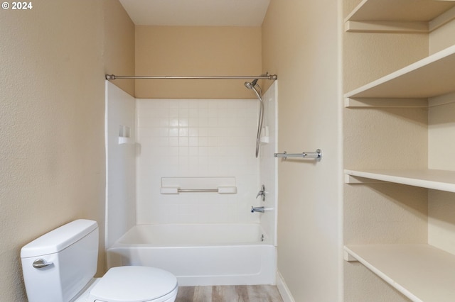 bathroom with tiled shower / bath combo, hardwood / wood-style flooring, and toilet