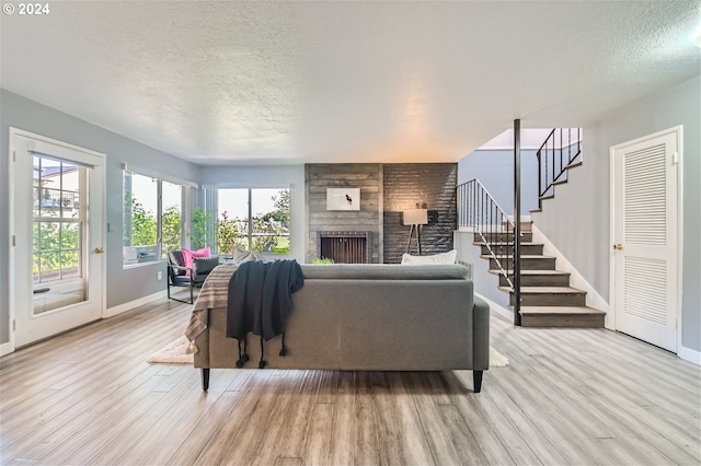 living room featuring a large fireplace, light hardwood / wood-style flooring, and a textured ceiling