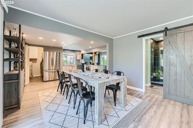 dining area with a barn door and light hardwood / wood-style floors