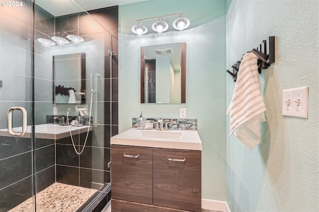 bathroom featuring a shower with door and vanity