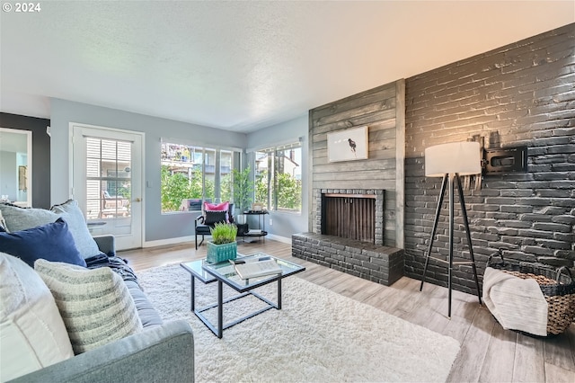 living room featuring a fireplace, wood-type flooring, and a textured ceiling