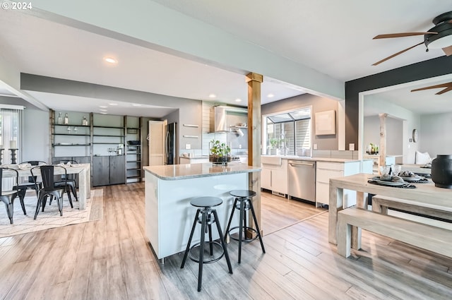 kitchen with white cabinets, a center island, appliances with stainless steel finishes, and light hardwood / wood-style flooring