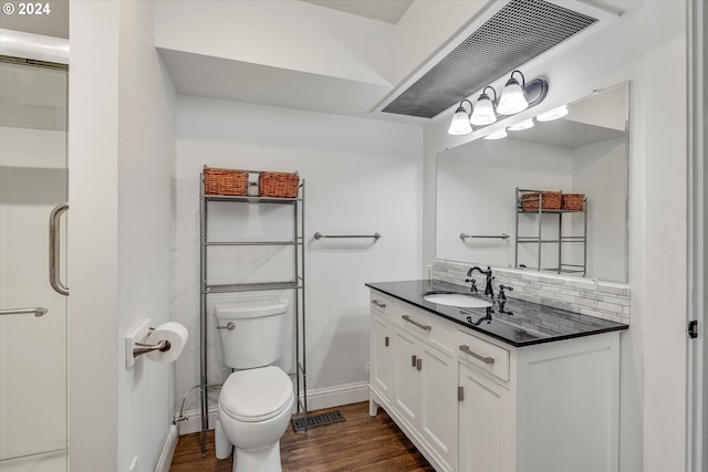 bathroom featuring toilet, wood finished floors, vanity, backsplash, and baseboards