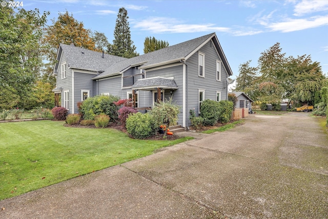view of front of house with roof with shingles and a front yard